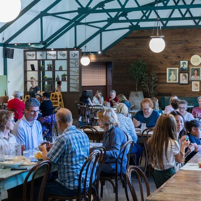 Busy dining room with guests at wooden tables.